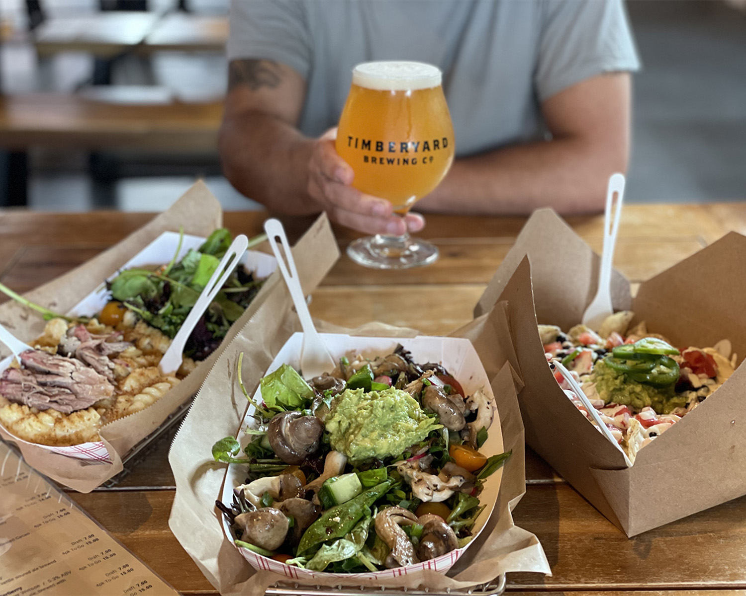 an assortment of food dishes with a man holding a beer